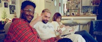 three people sitting on a couch in a living room