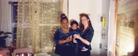 two women holding a baby in front of a curtain