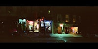 a city street at night with a neon sign