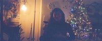 a woman holding a glass of wine in front of a christmas tree