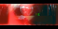 a person in a red hoodie standing in front of a red disco ball